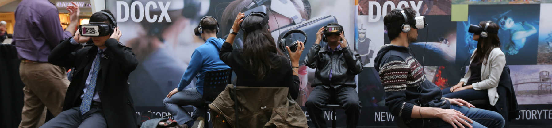 Six individuals sit in chairs with virtual reality headsets on.
