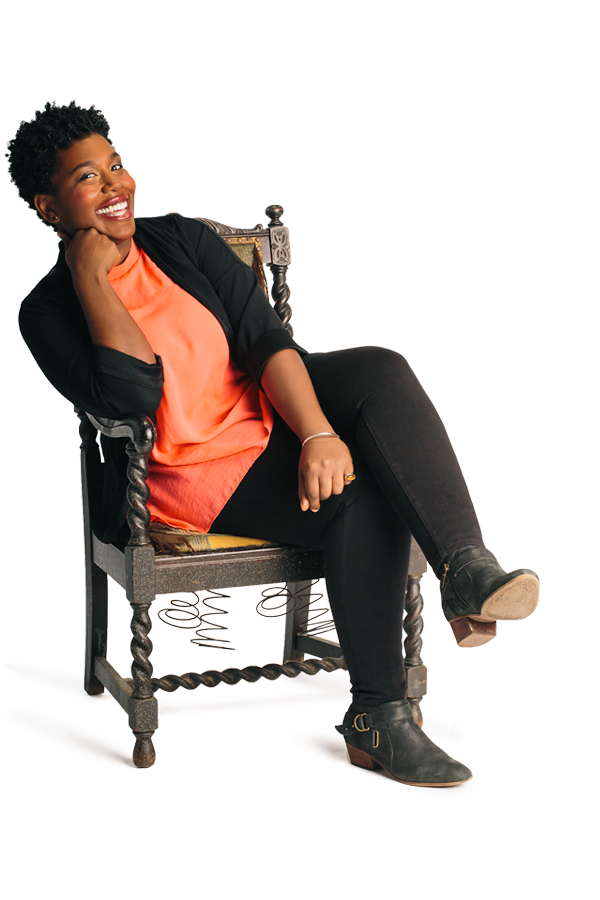Sitting on an old chair, Meghan Swaby crosses her legs and smiles at the camera