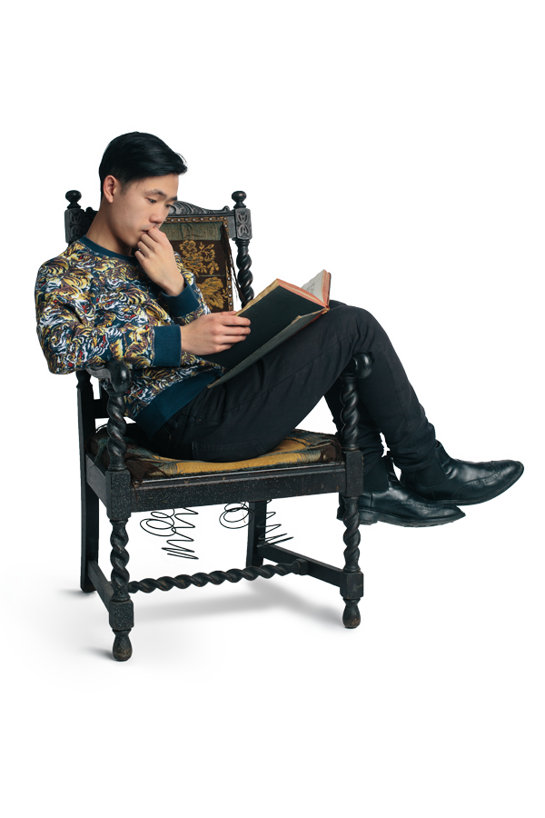 Theatre Artist Jeff Ho sits on a chair reading a book of plays