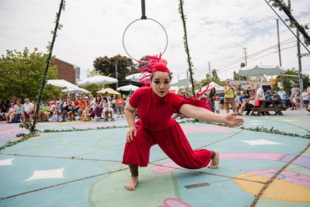 A circus performer dances in front of a crowd
