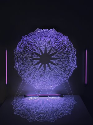 neon light image of a Kolam pattern projected on a dark wall