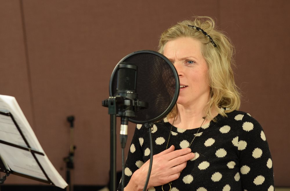 Actor Liisa Repo-Martell speaks into an microphone in a recording booth