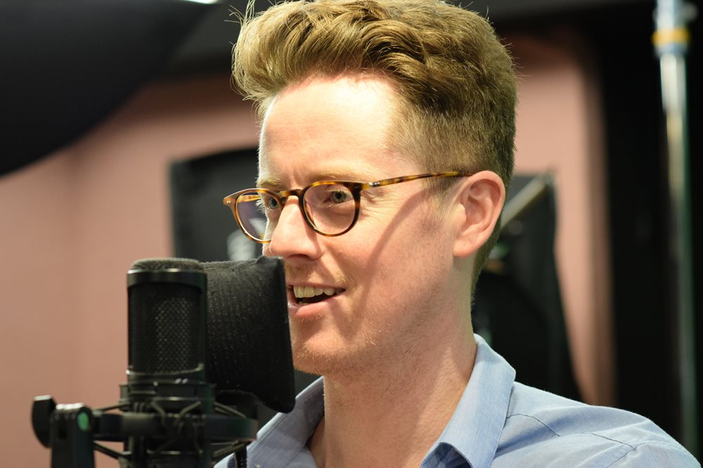 Actor David Patrick Flemming speaks into an microphone in a recording booth