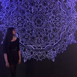 photo of a visual artist standing beside her art creation