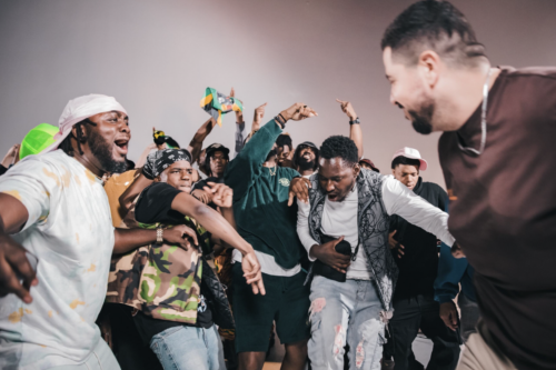 A group of people celebrate, jumping, shouting, hands in the air.