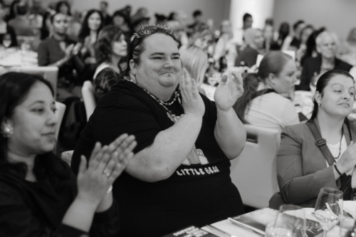 Rainbow Hunt applauds while seated at a table at the 2026 Mayor's Arts Lunch.